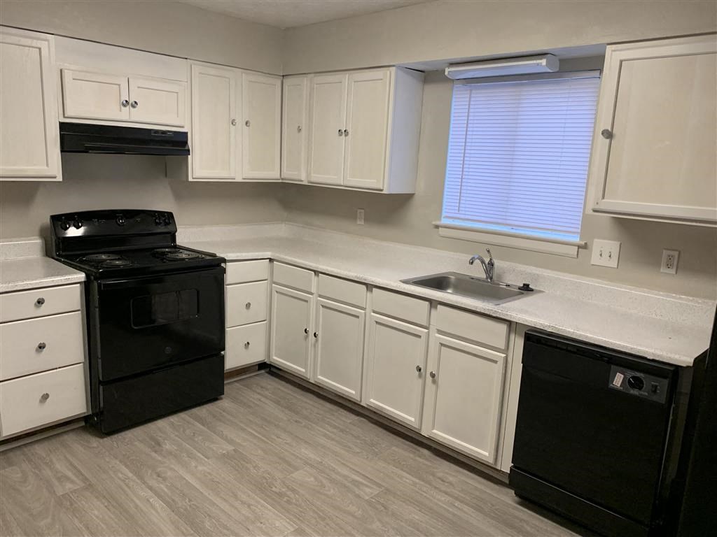 a kitchen with white cabinets and a wooden table at Hidden Woods, Decatur, Georgia