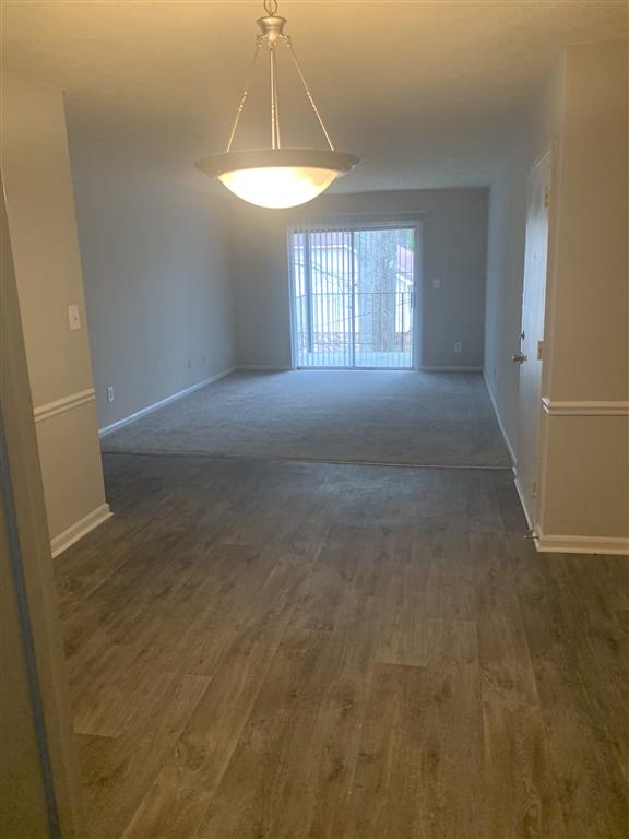 an empty living room with a wood floor and a ceiling light