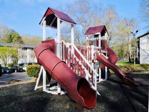 a playground with a red slide and a white playset
