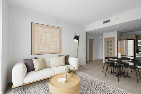 A living room with a white couch and a large abstract painting on the wall.