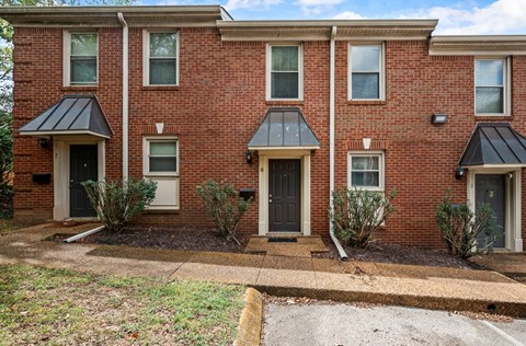 A red brick house with a black roof and a grey door.
