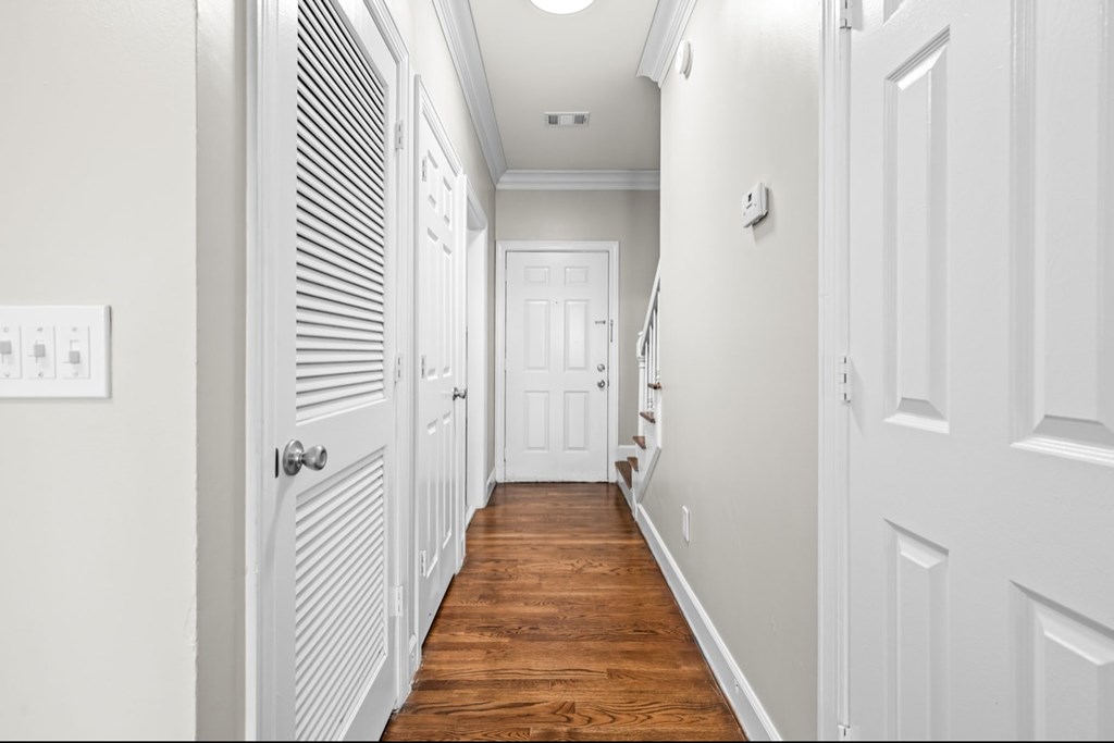 A long hallway with white doors and wood floors.