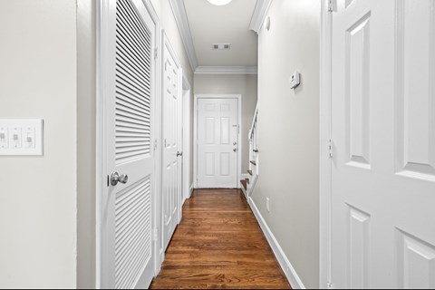 A long hallway with white doors and wood floors.