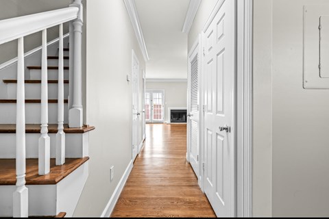 A long hallway with white walls and a wooden floor.