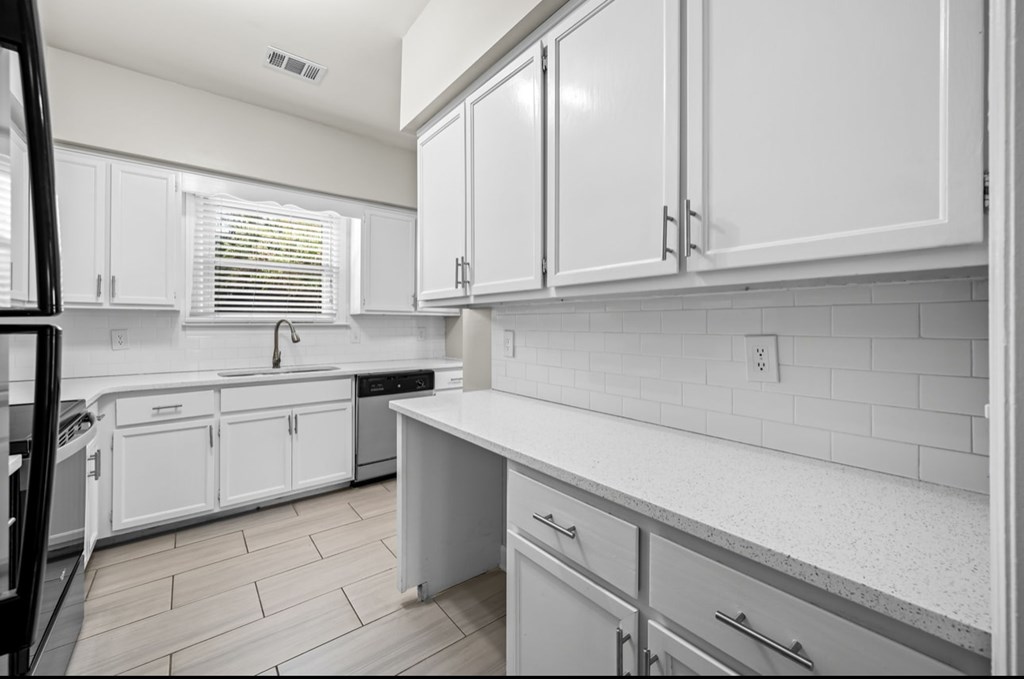 A kitchen with white cabinets and a tiled backsplash.