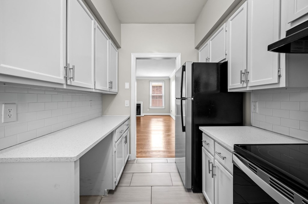 A kitchen with white cabinets and a black refrigerator.