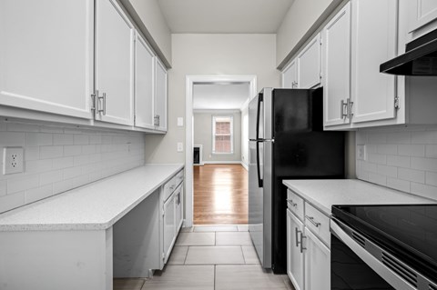 A kitchen with white cabinets and a black refrigerator.