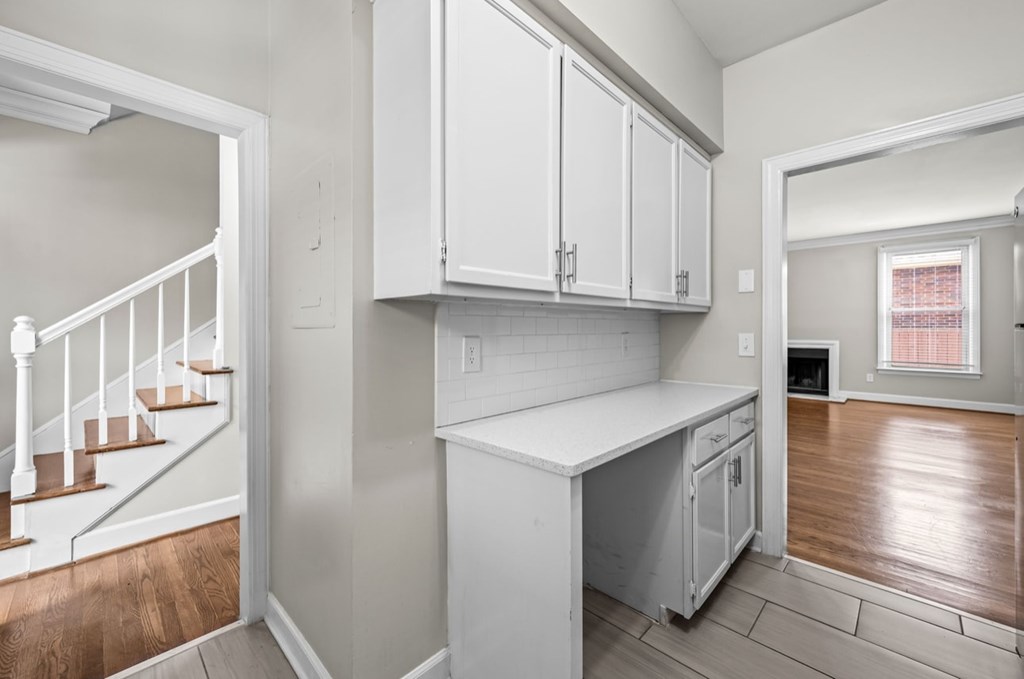 A kitchen with white cabinets and a wooden floor.