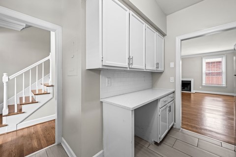 A kitchen with white cabinets and a wooden floor.