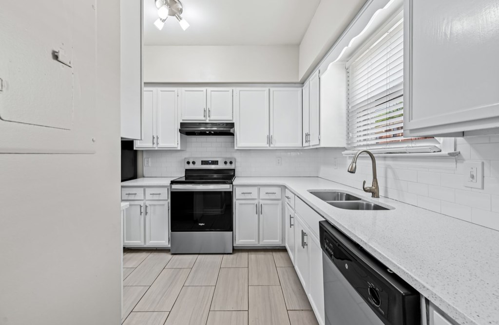 A modern kitchen with white cabinets and stainless steel appliances.