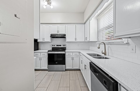 A modern kitchen with white cabinets and stainless steel appliances.