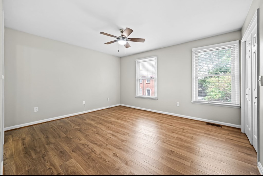A room with a ceiling fan and wooden flooring.