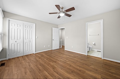 A room with a ceiling fan and wooden flooring.