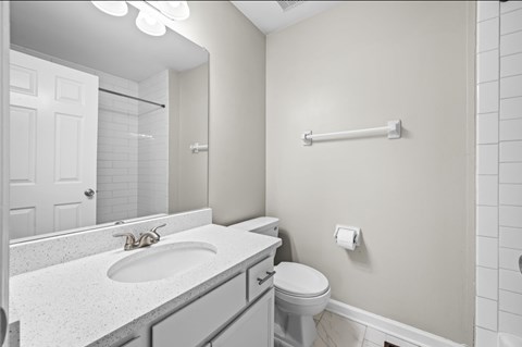 A white bathroom with a toilet, sink, and mirror.