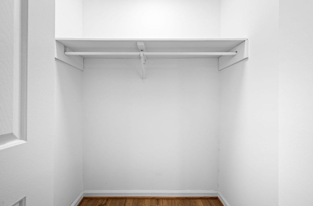 A white closet with a shelf and a door.