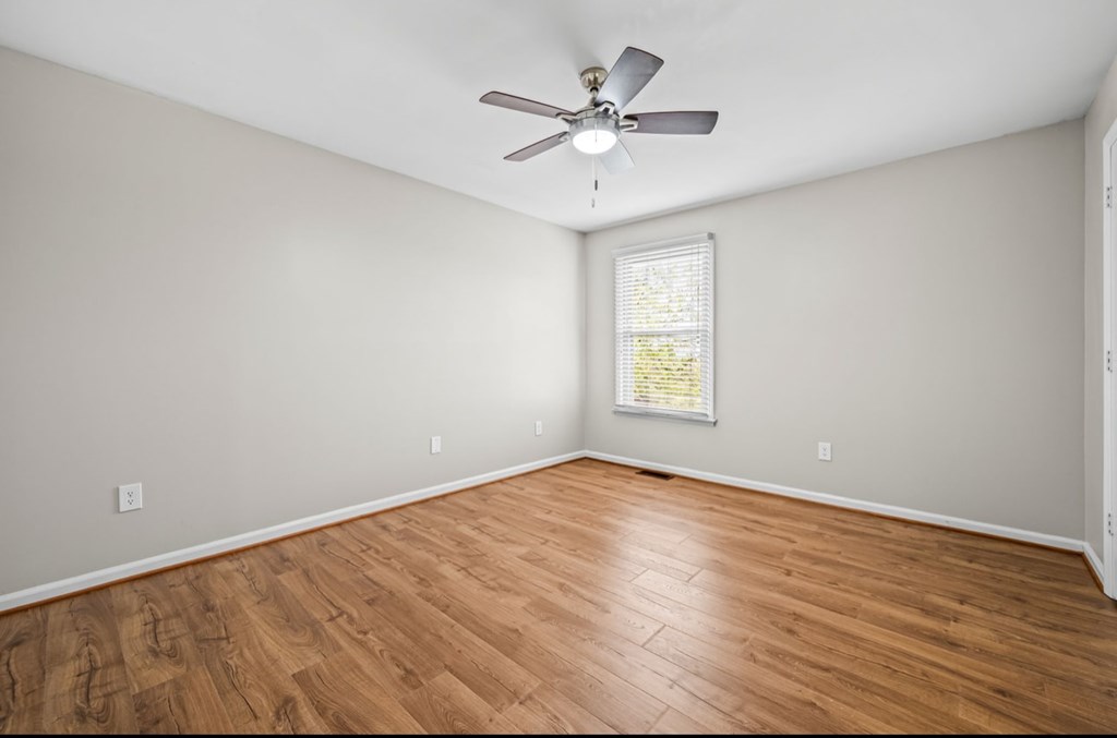 A room with a ceiling fan and a window with blinds.