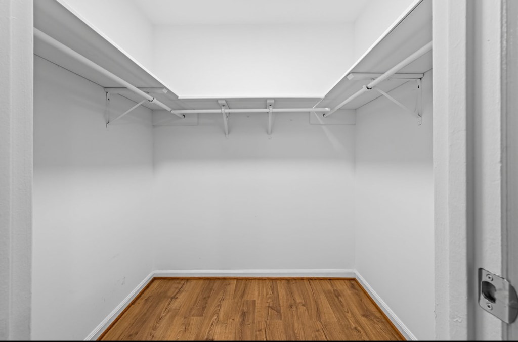 A white wall with a wooden floor and a metal rod on the wall.