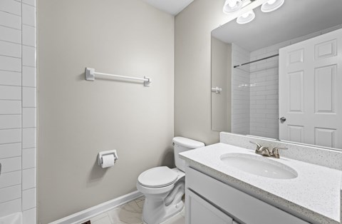A white bathroom with a toilet, sink, and mirror.