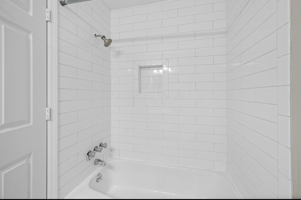 A white bathroom with a white tub and shower.