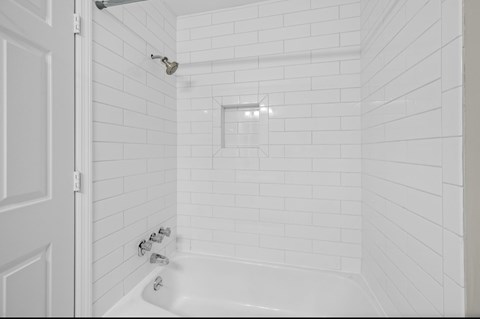 A white bathroom with a white tub and shower.