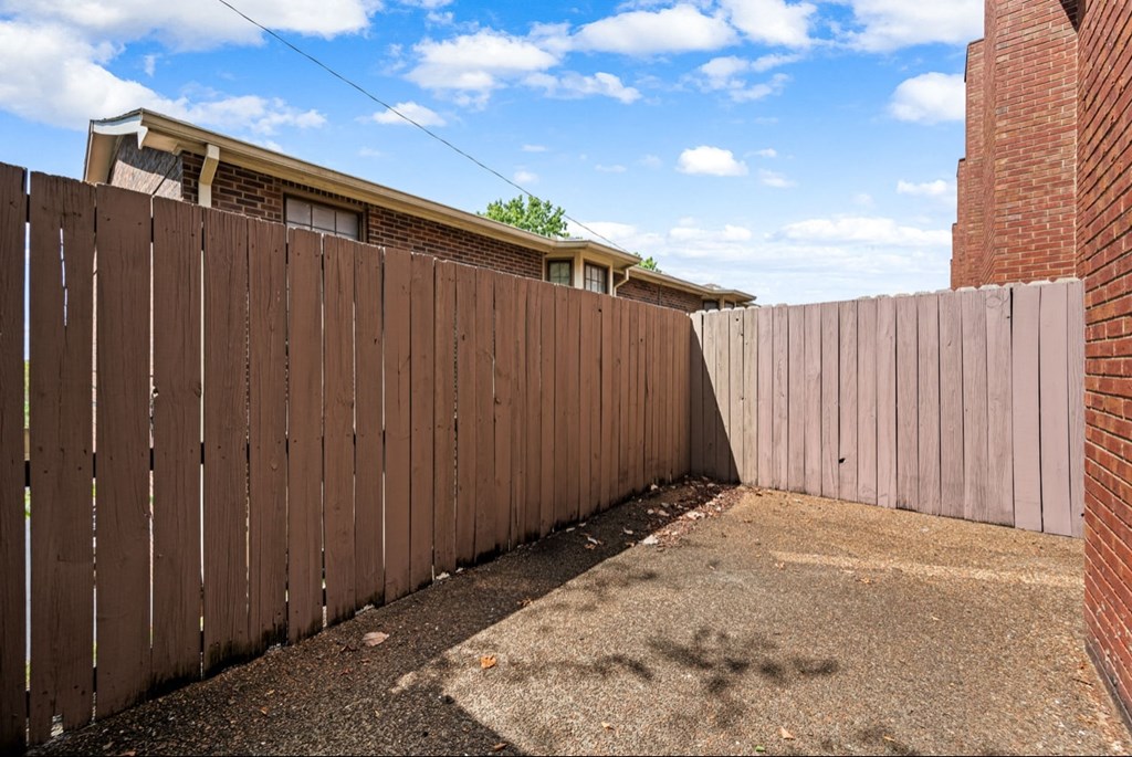 A brown wooden fence separates two backyards.