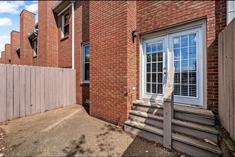 A red brick house with a white door and a wooden fence.