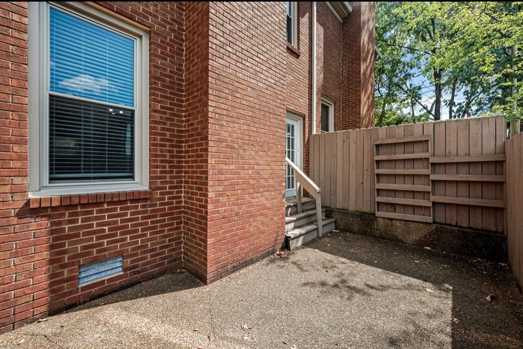 A red brick house with a window and a wooden fence.