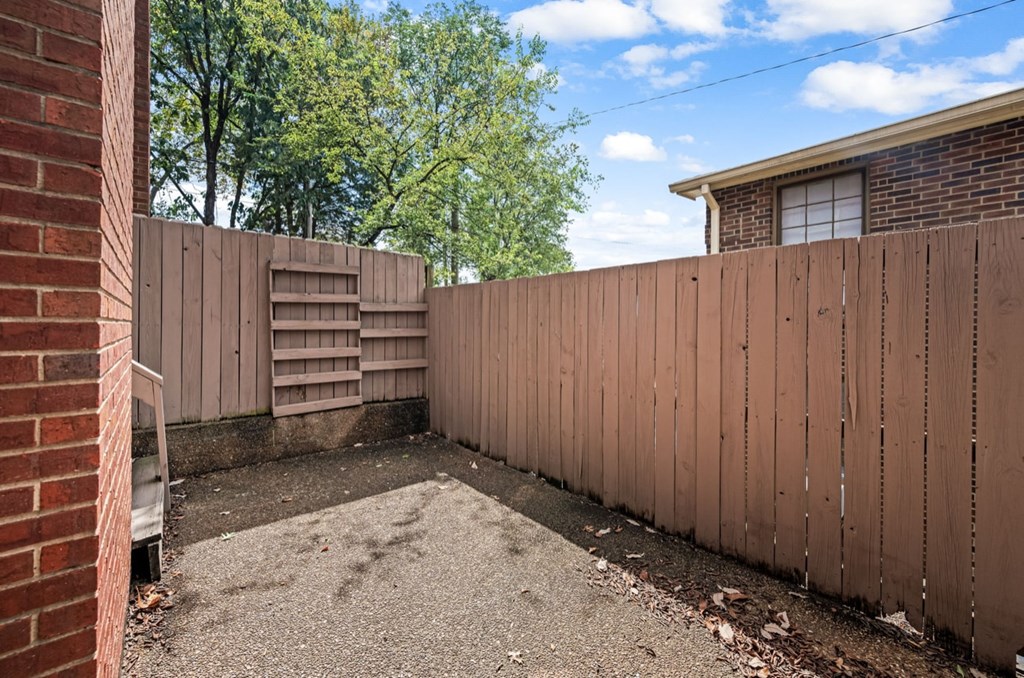 A backyard with a wooden fence and a brick wall.