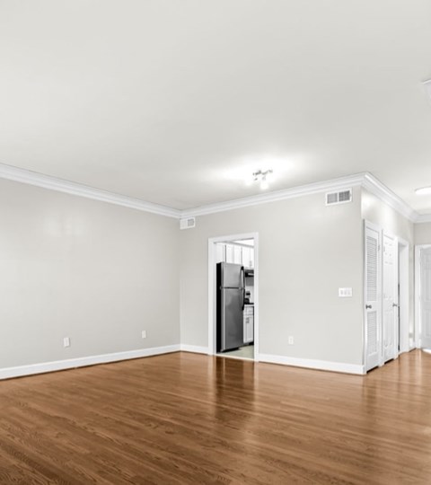 A kitchen with a refrigerator and wooden floors.