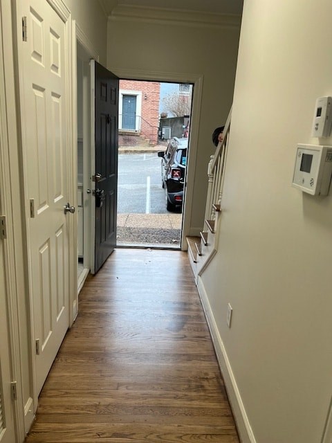 A hallway with a door on the left and a wall-mounted thermostat on the right.