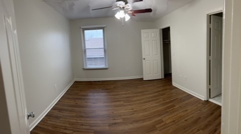 A room with a ceiling fan and a window with blinds.