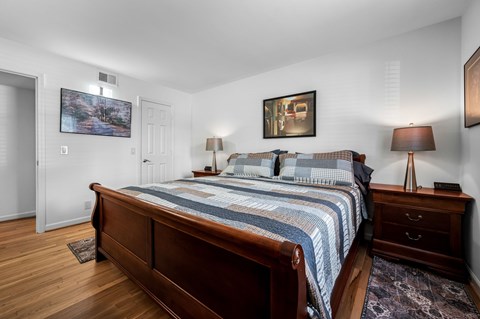 A bedroom with a large bed and a painting on the wall.