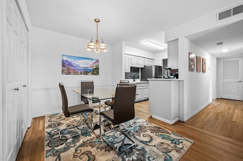 A dining room with a table and chairs and a painting on the wall.