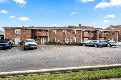 A parking lot in front of a brick apartment building.