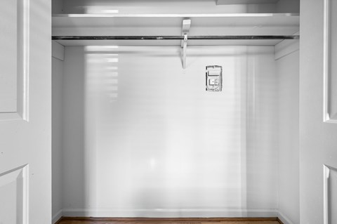 A white hallway with a door on the left and a sign on the wall.