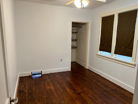 a bedroom with a wood floor and a window and a closet