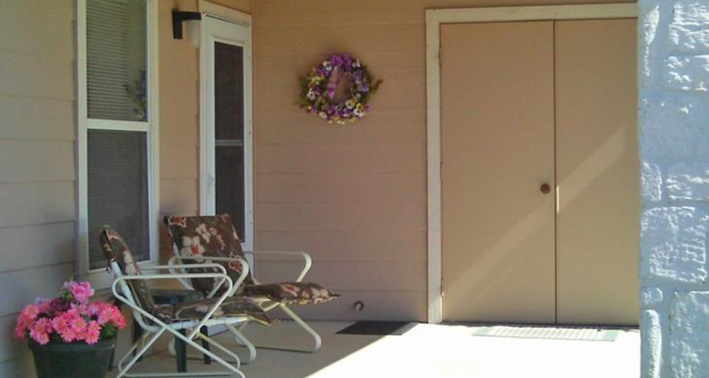 a porch with chairs and a table and a wreath on the wall