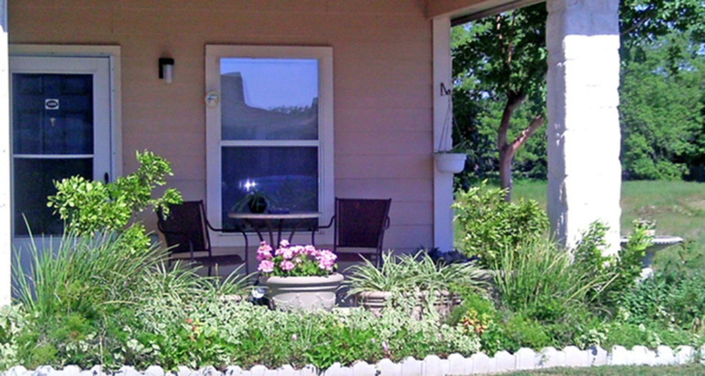 a front porch with a table and chairs and flowers in a pot