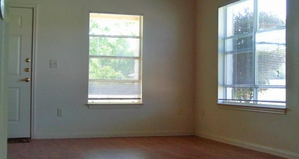an empty living room with two windows and a door