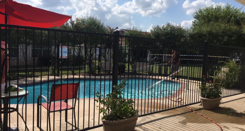 a swimming pool is behind a black fence