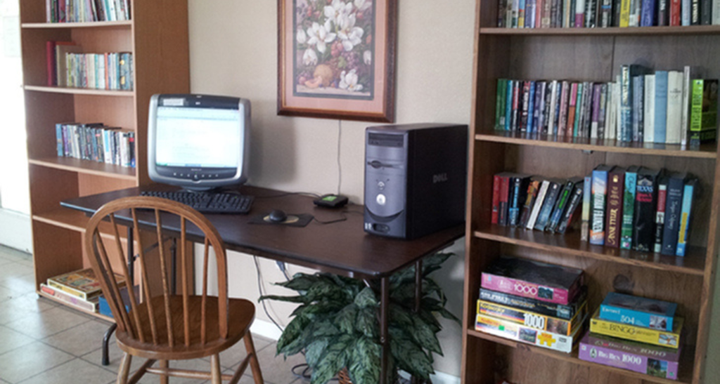 a desk with a computer and a book shelf