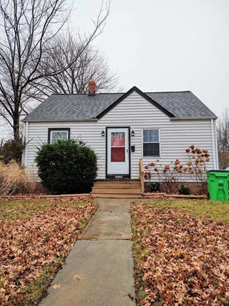 a white house with a red door and a sidewalk