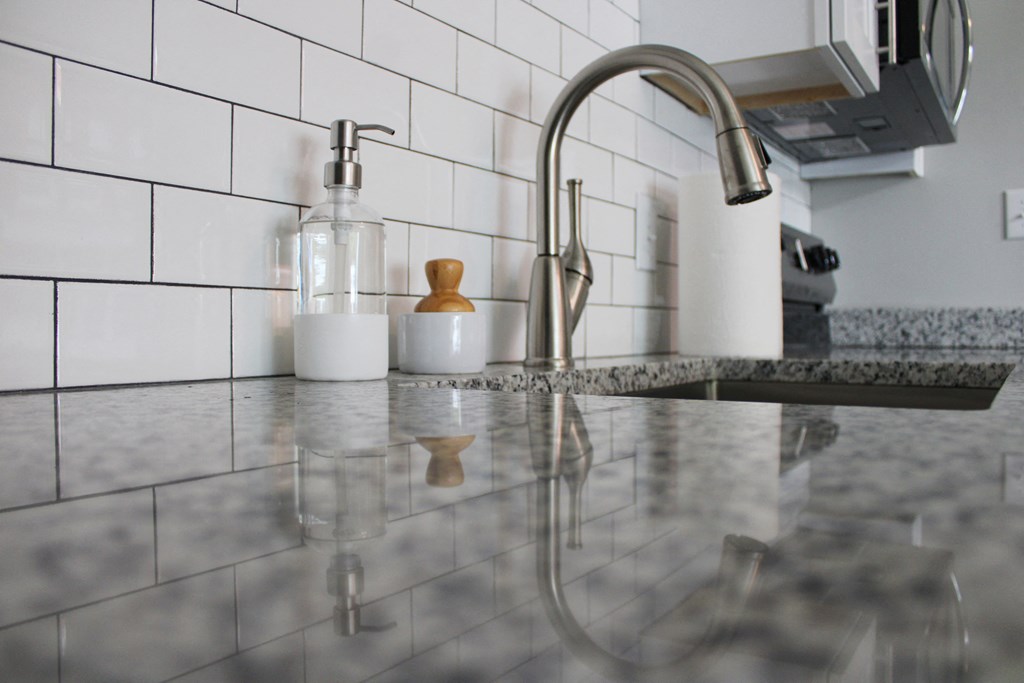 a kitchen sink with a chrome faucet and a bottle of soap on it