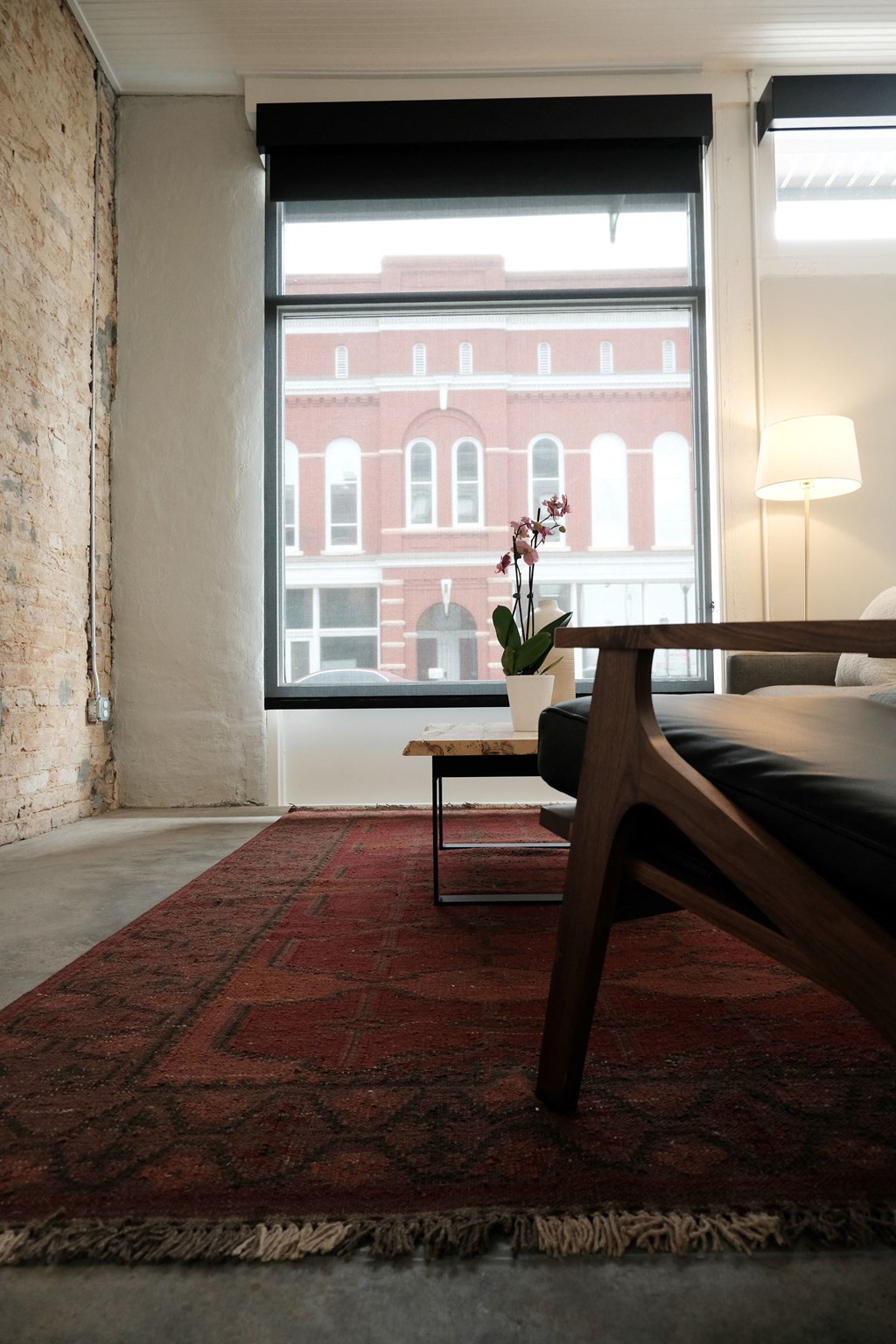 a living room with a large window and a red rug