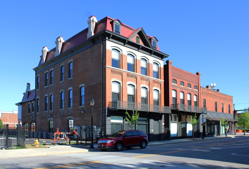 a red brick building on a city street with a red car