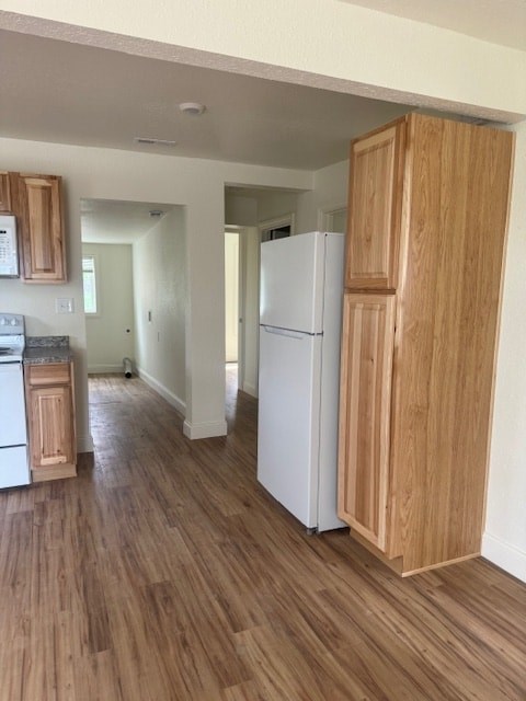 A kitchen with a white refrigerator and wooden cabinets.