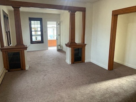 an empty living room with pillars and a fireplace