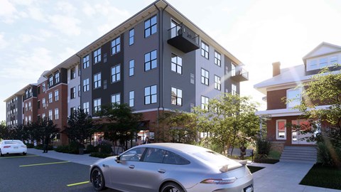 A silver car is parked in a parking lot in front of a building.