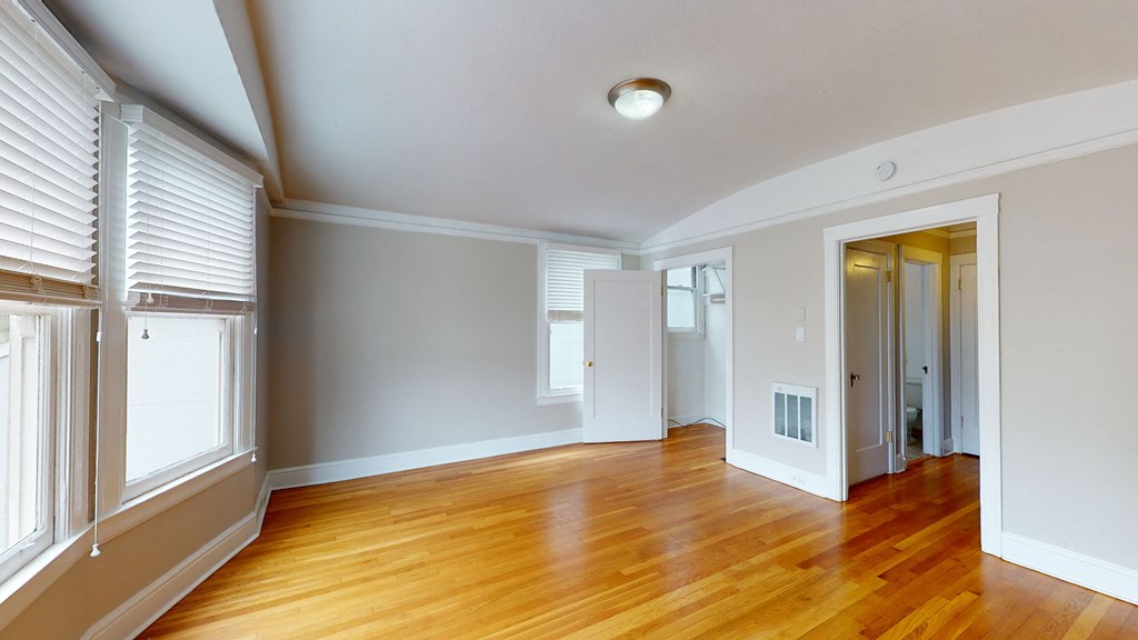 an empty living room with wood floors and white walls