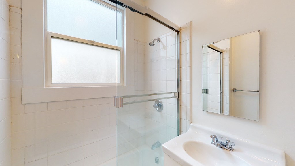 a white bathroom with a shower and a sink